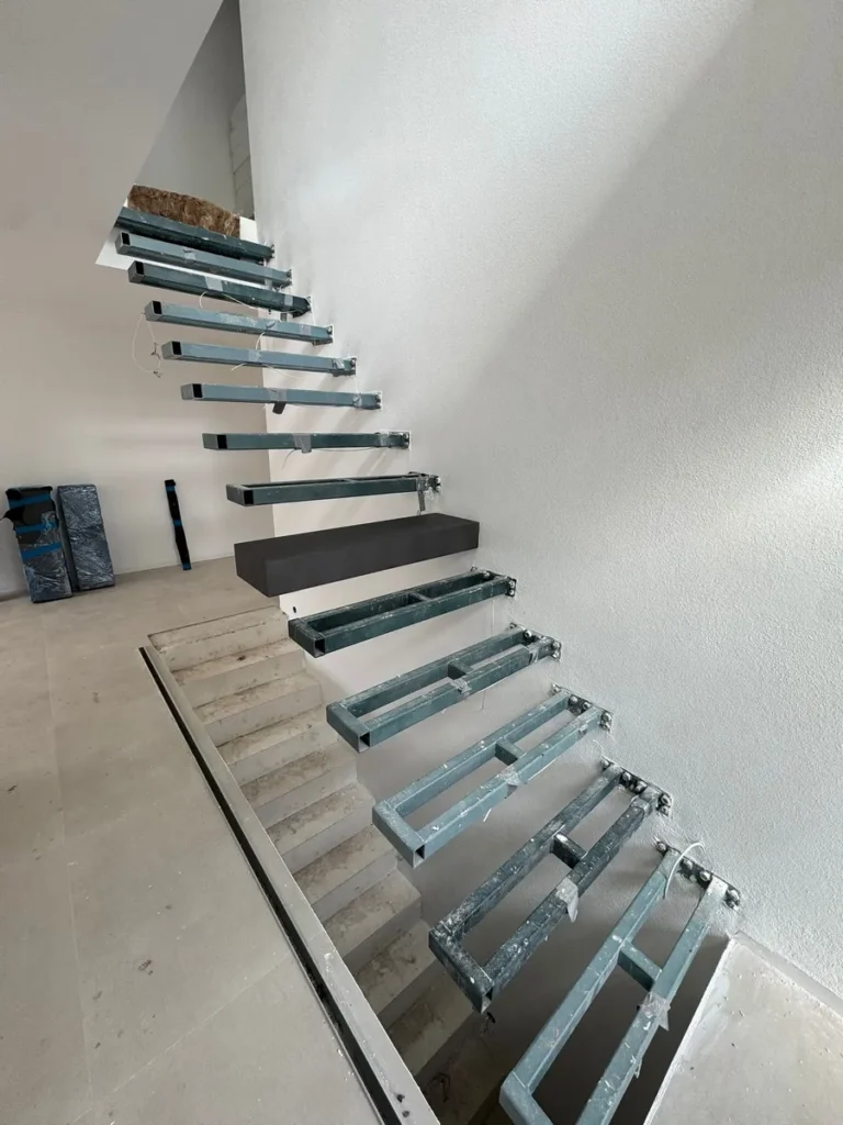 Unfertige freitragende Treppe im Rohbauzustand. Die Stahlkonstruktion der Treppenstufen ist sichtbar, bereit für die individuelle Gestaltung als Massanfertigung. Detailaufnahme der Treppenmontage.